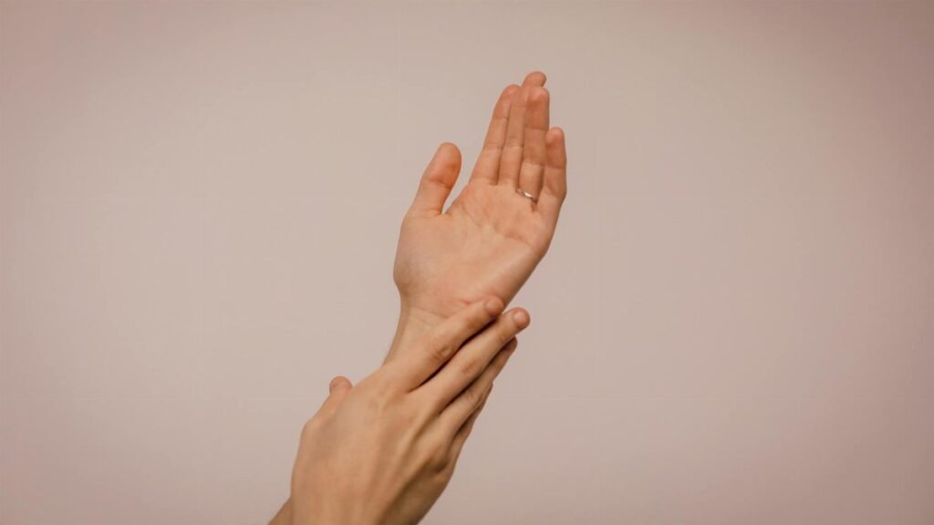 Close-up of hands gently caressing each other, symbolizing self-care and softness.