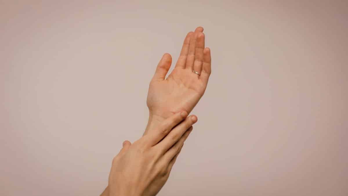 Close-up of hands gently caressing each other, symbolizing self-care and softness.