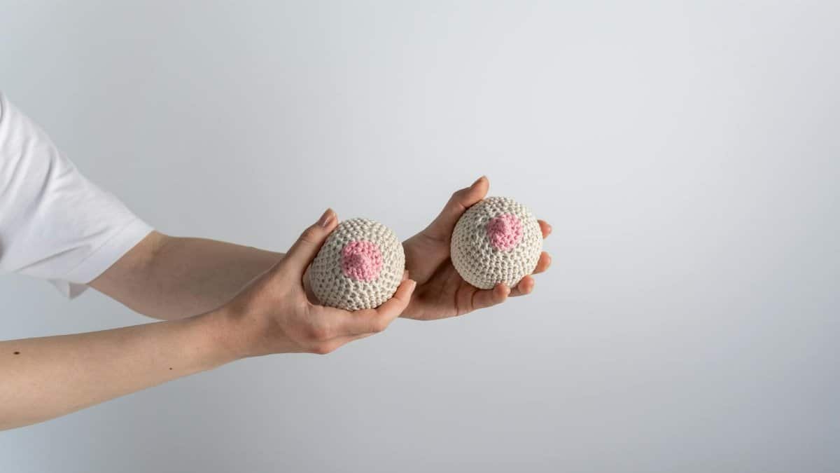 Hands holding crocheted breast models for breast cancer awareness.