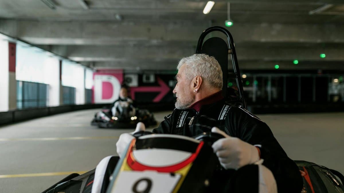 Senior man driving a go-kart indoors, showcasing the excitement of kart racing.