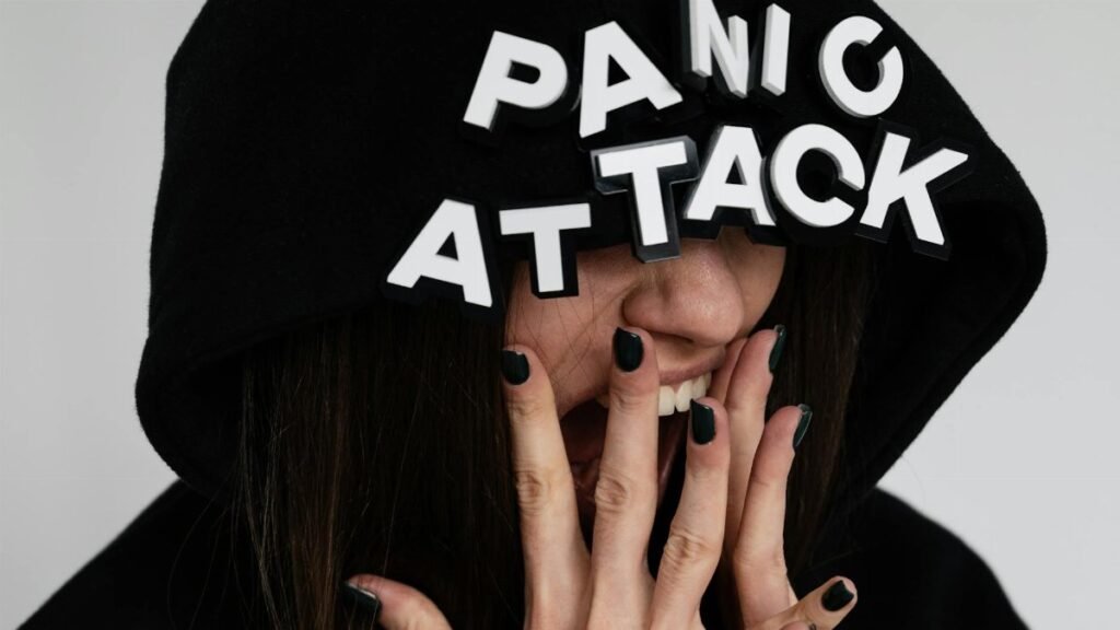 Close-up of a woman in a hoodie with 'panic attack' text, conveying anxiety.