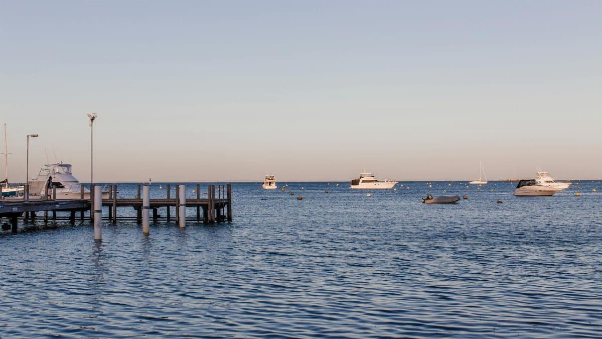 Calm sea with boats at the marina during a clear day, ideal for stock imagery.