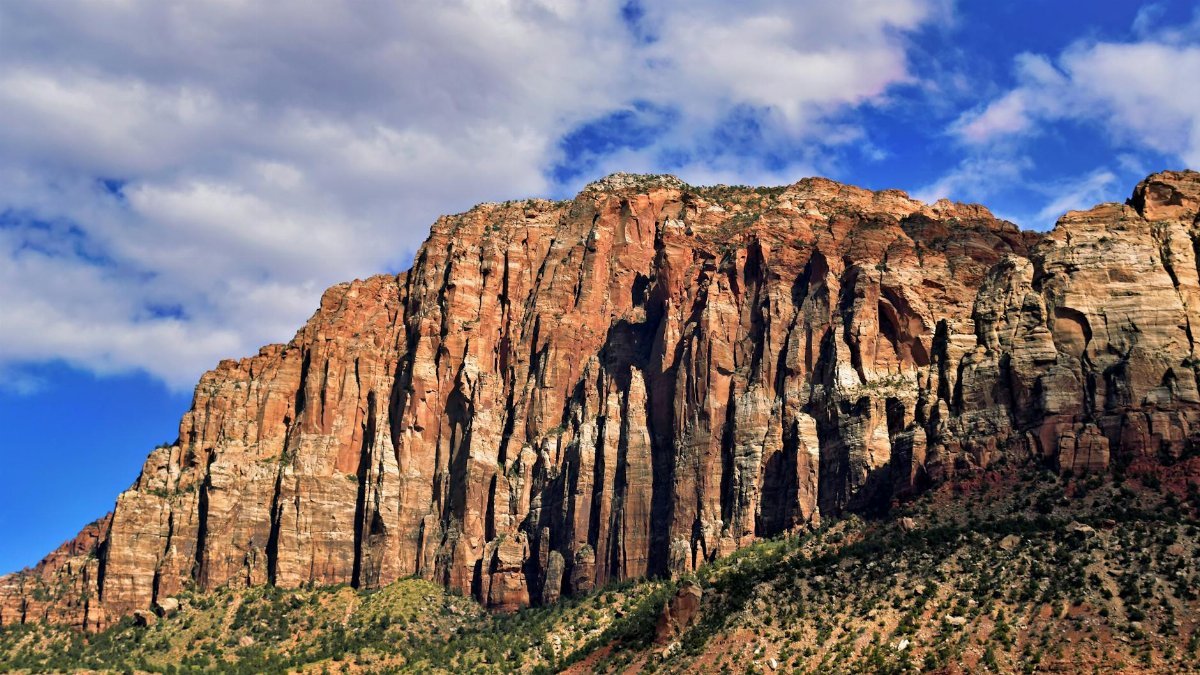 Scenic view of towering sandstone formations under a bright blue sky in Zion National Park, Utah.