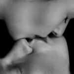 Emotional black and white close-up of a couple sharing an intimate kiss, capturing raw love.