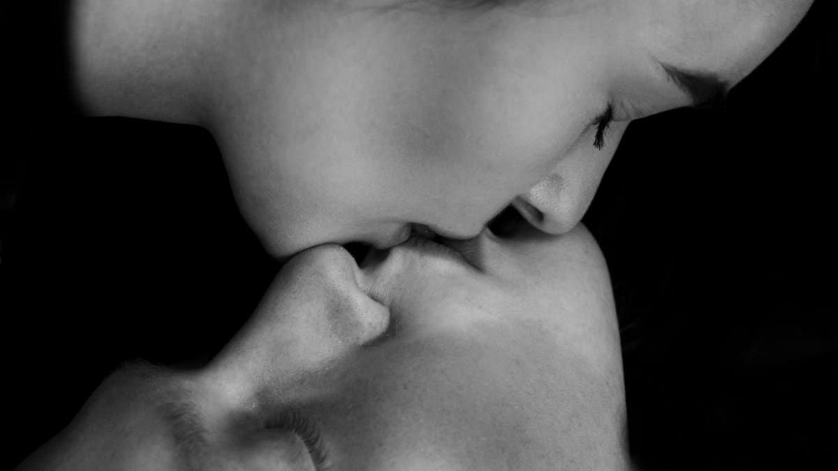 Emotional black and white close-up of a couple sharing an intimate kiss, capturing raw love.