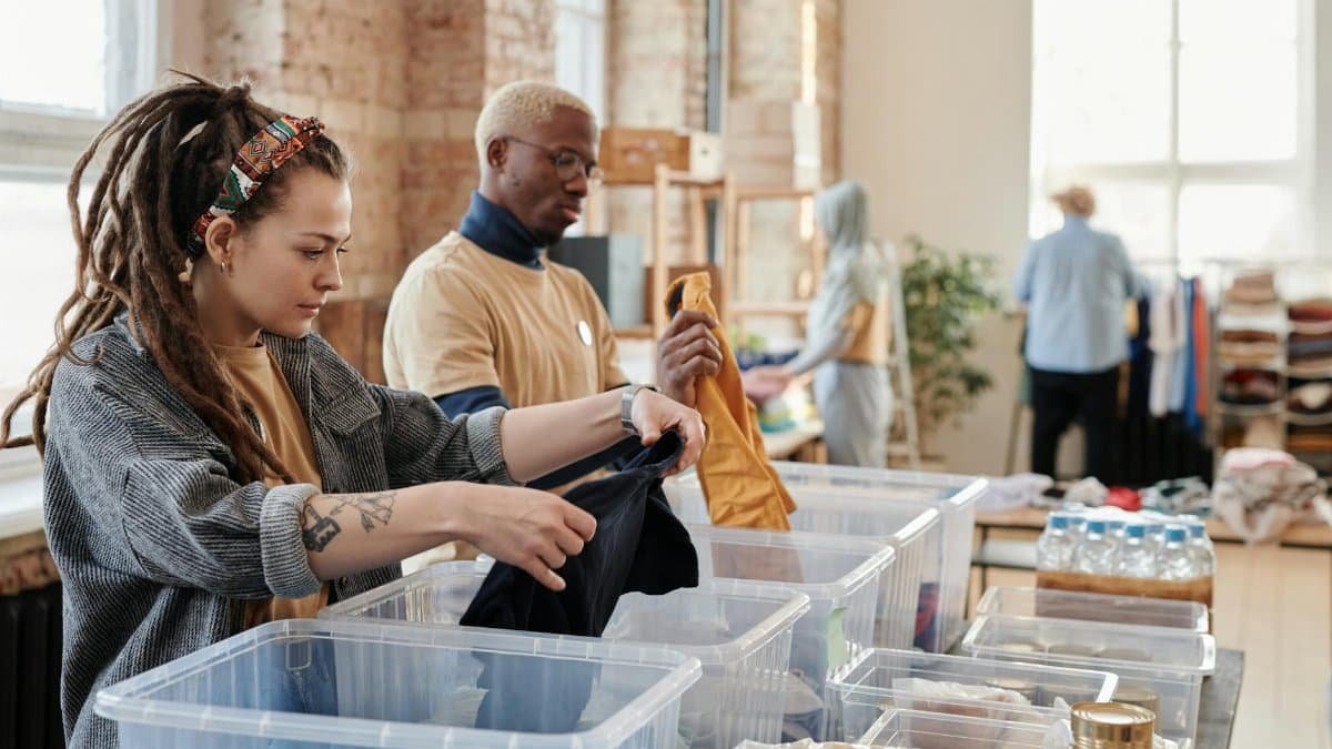 Volunteers organize donated clothing at a donation center, fostering community support and sustainability.