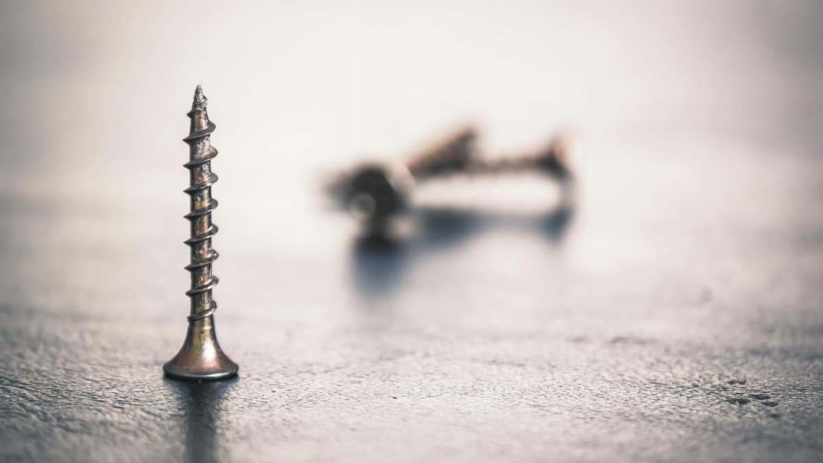 High-detail close-up of sharp metal screws on a textured surface with soft focus.
