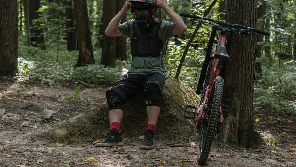 Cyclist taking a break on a forest trail with his mountain bike.
