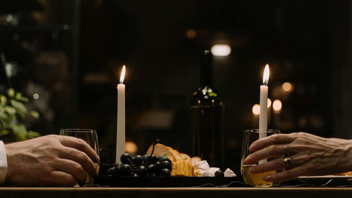 Intimate dinner setup with wine, cheese, and candles on a wooden table.