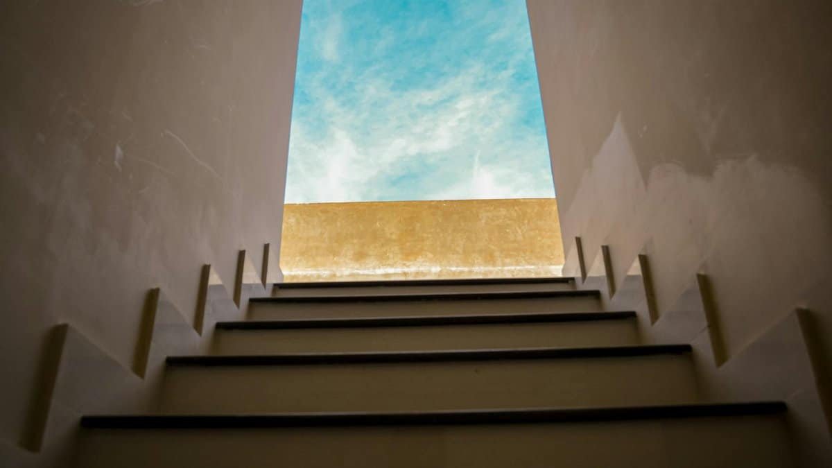 View of an upward staircase leading towards a clear blue sky, symbolizing new beginnings.