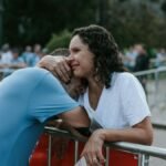 An emotional embrace between two adults at an outdoor event provides a touching moment.