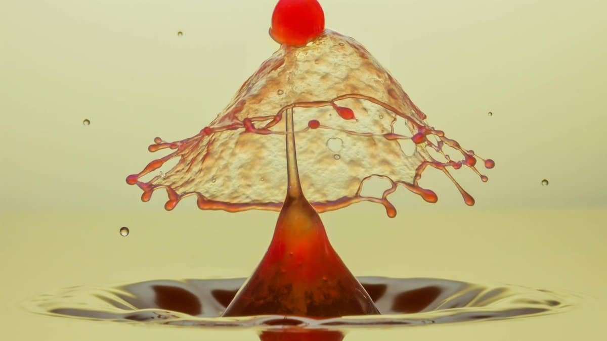 Macro shot capturing a water drop collision creating a colorful umbrella-like splash.