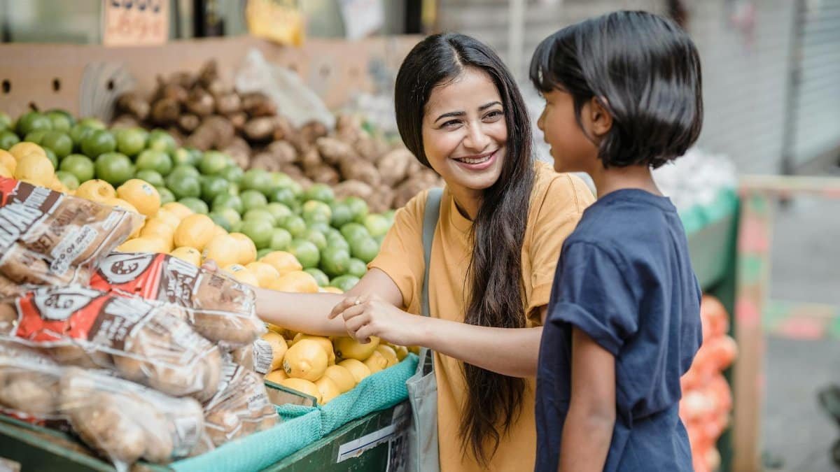 A woman and child selecting fresh fruits and vegetables at an outdoor market. Captures joy and healthy living.