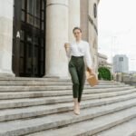 Fashionably dressed woman walking down steps with coffee and paper bag