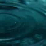 Abstract close-up of water ripples forming mesmerizing patterns with teal hues.