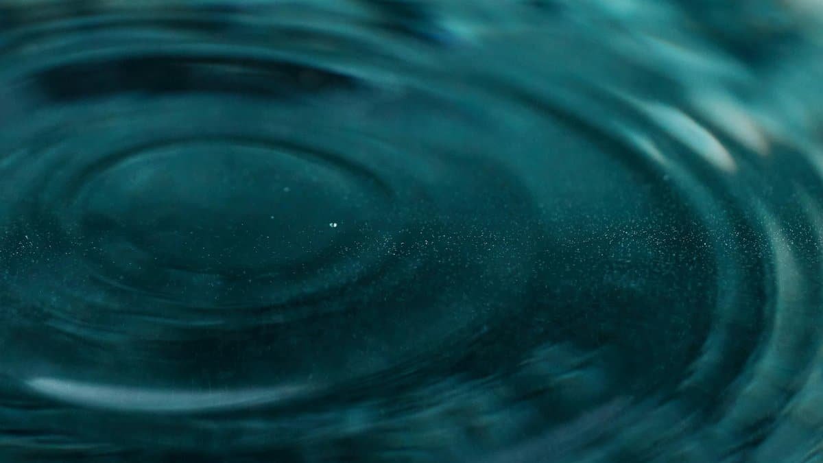 Abstract close-up of water ripples forming mesmerizing patterns with teal hues.