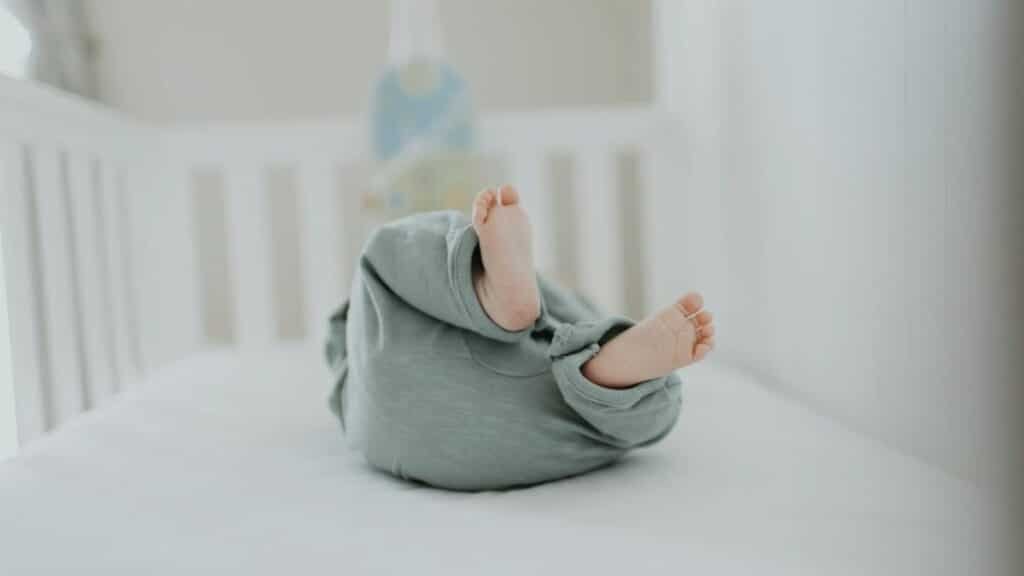 Cute baby feet in pajamas on a soft white crib. Perfect for children's room decor.
