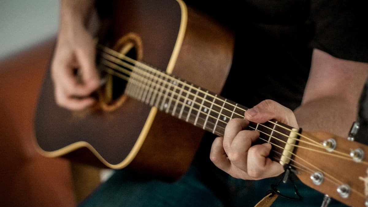 A musician strums chords on an acoustic guitar, showcasing musical talent.