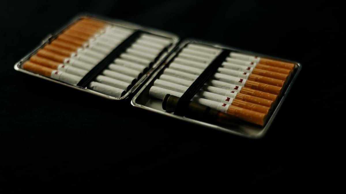 An open cigarette case filled with cigarettes, placed on a dark surface, conveying a mood of smoking and lifestyle.