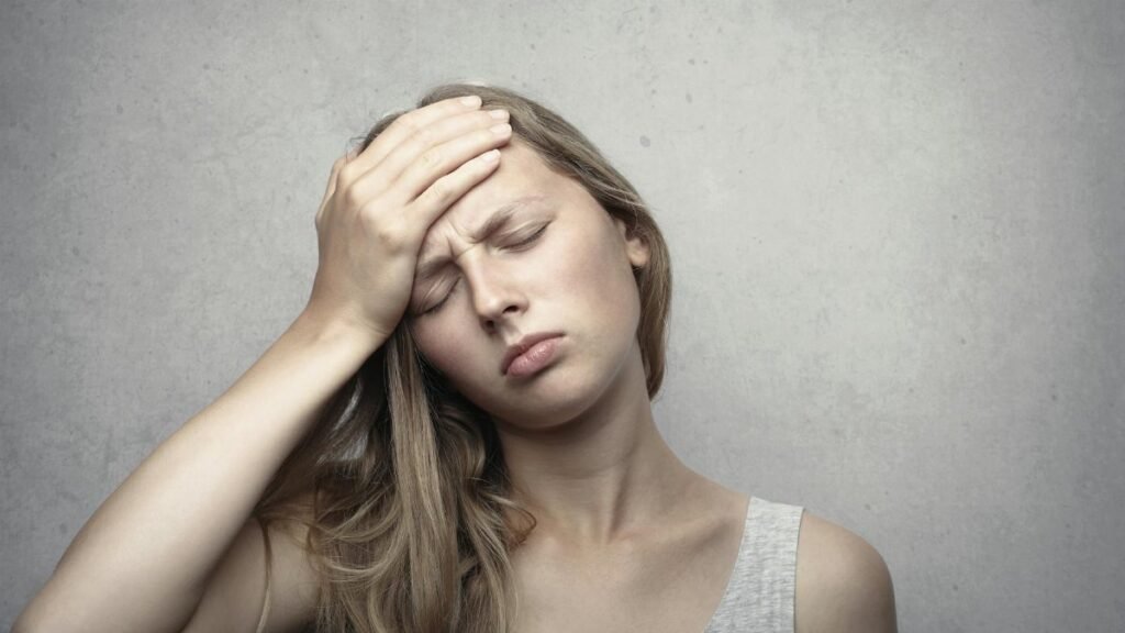 A woman in distress holding her head, expressing emotion and fatigue.