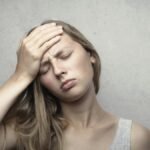 A woman in distress holding her head, expressing emotion and fatigue.