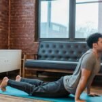 Side view full body of concentrated male lying on sports mat and stretching back muscles in Bhujangasana during yoga training
