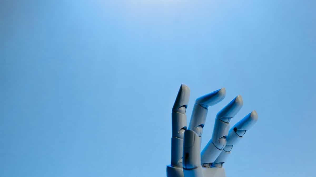 Robotic hand with articulated fingers reaching towards the sky on a blue background.
