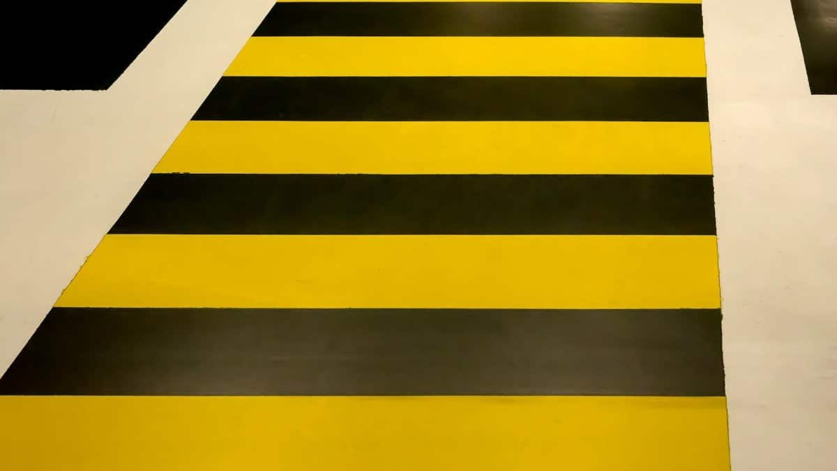 Vibrant yellow and black striped pedestrian crosswalk with geometric pattern.