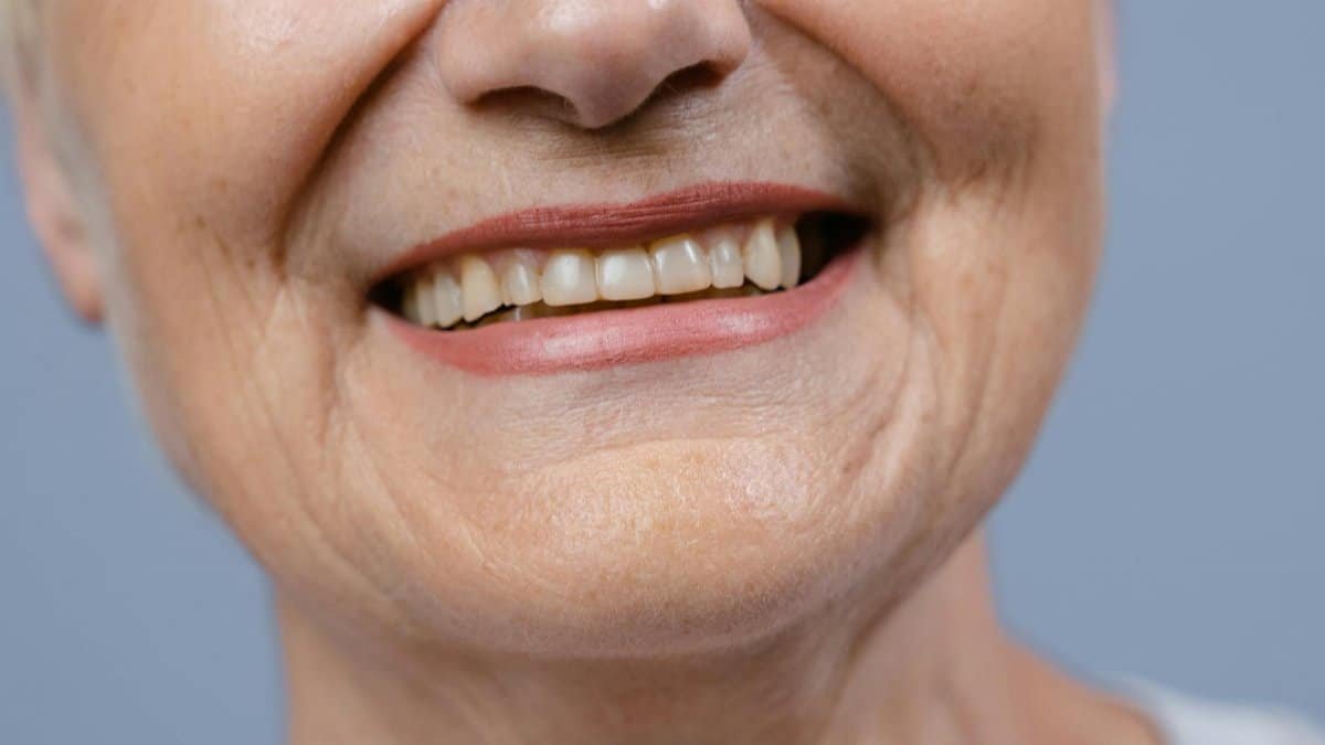 A detailed close-up of a senior woman's smile showcasing her natural teeth and wrinkles.