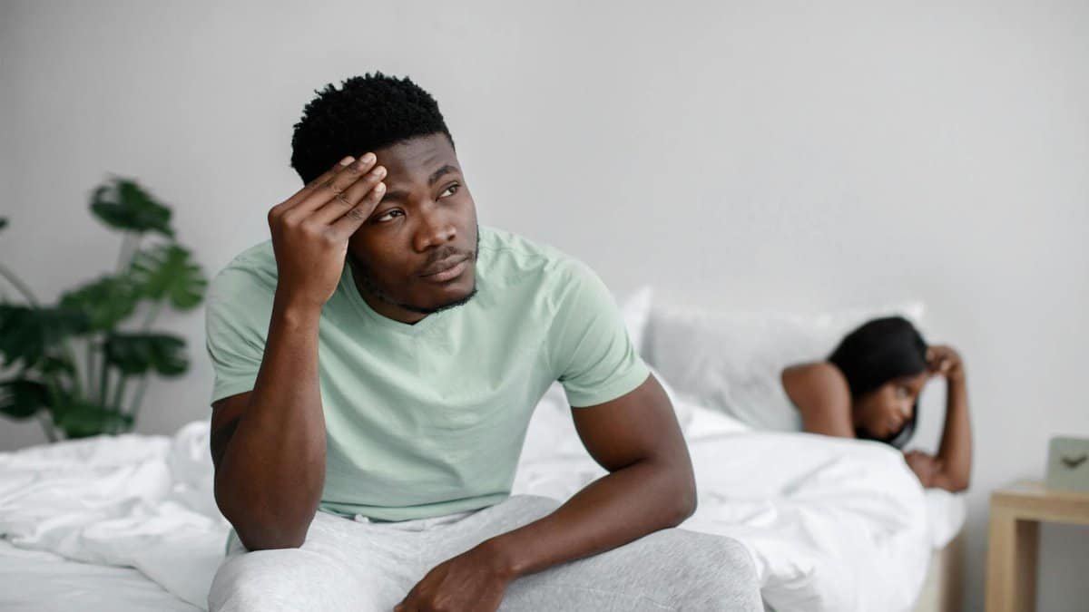 Troubled couple experiencing conflict in a bedroom setting, expressing emotional distress.