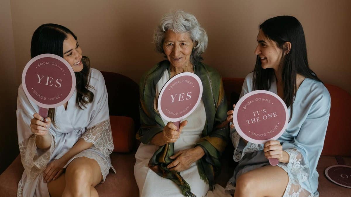 Grandmother and bridesmaids share joy holding signs during wedding preparations.