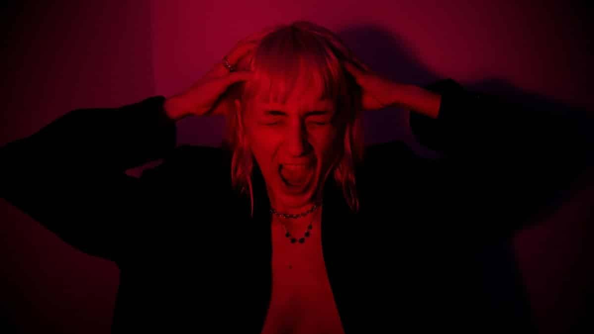 Portrait of a woman expressing strong emotion in dramatic red lighting.