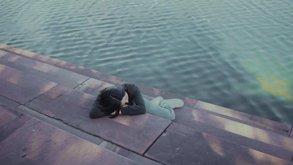 A woman rests peacefully by the water, embodying serenity and calm in Austin, Texas.