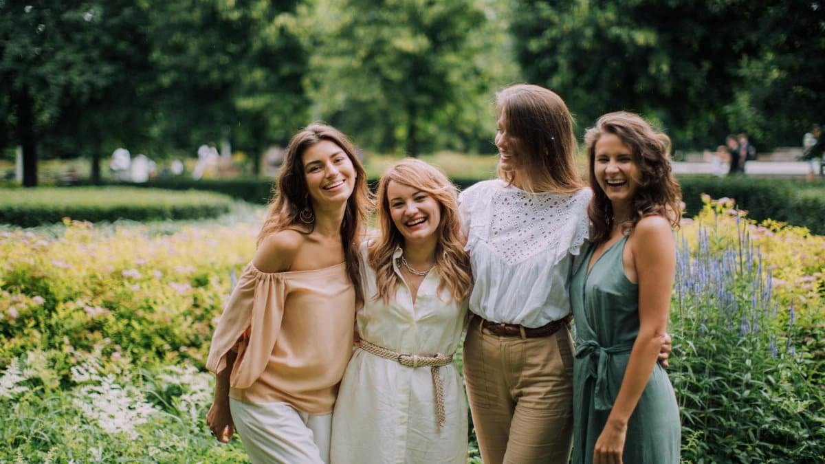 A joyful group of women standing together in a sunny park, symbolizing friendship and togetherness.