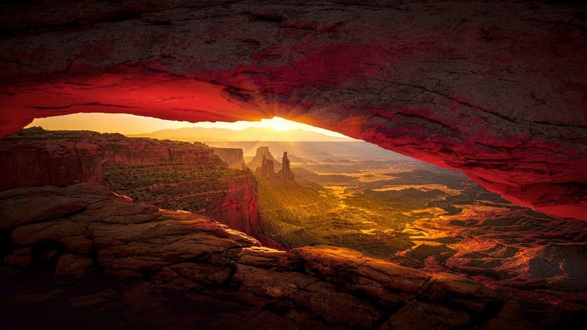Captivating sunrise view through Mesa Arch in Canyonlands National Park showcasing vibrant desert landscape.