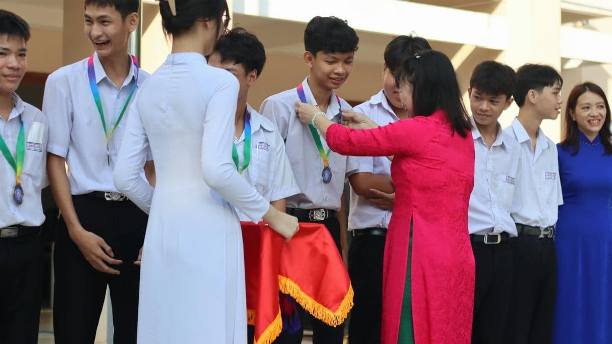 Students receiving medals from teachers during a school award ceremony outdoors.