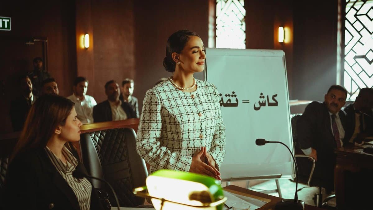 Middle Eastern woman confidently presents in a Baghdad courtroom with audience attention.
