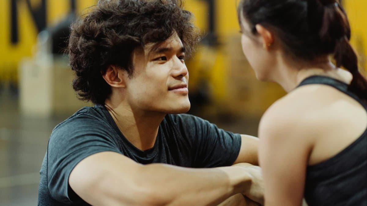 A young couple connects face-to-face in an intimate gym setting, fostering closeness and understanding.