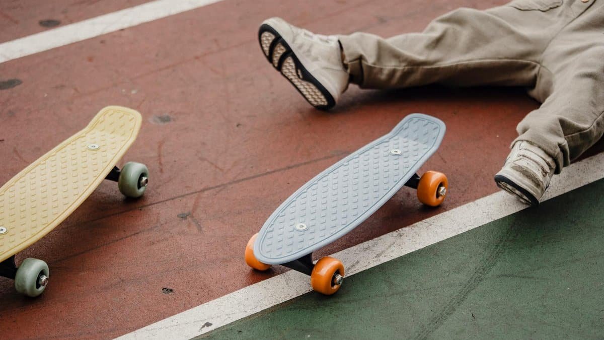 Person relaxing on the ground with skateboards nearby in a park.
