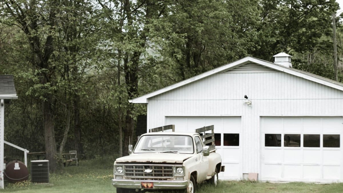 A classic vintage truck parked beside a rustic garage amidst lush greenery in Asheville, NC.