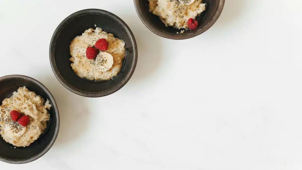Bowl of oatmeal with banana, raspberry, and chia seeds on a white background.