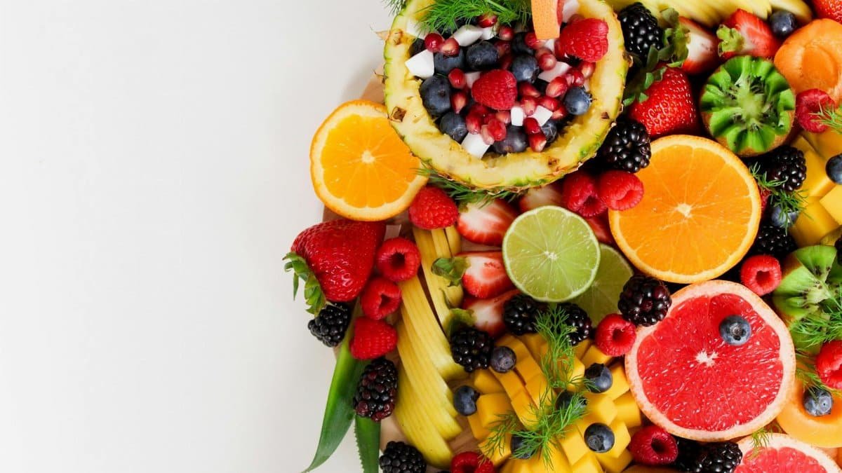 Colorful flat lay of assorted tropical fruits including pineapple, berries, and citrus.
