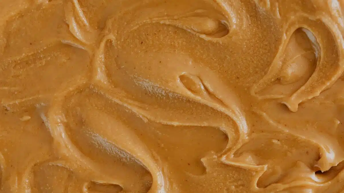 Smooth and creamy peanut butter texture with swirls, perfect for food and culinary themes.