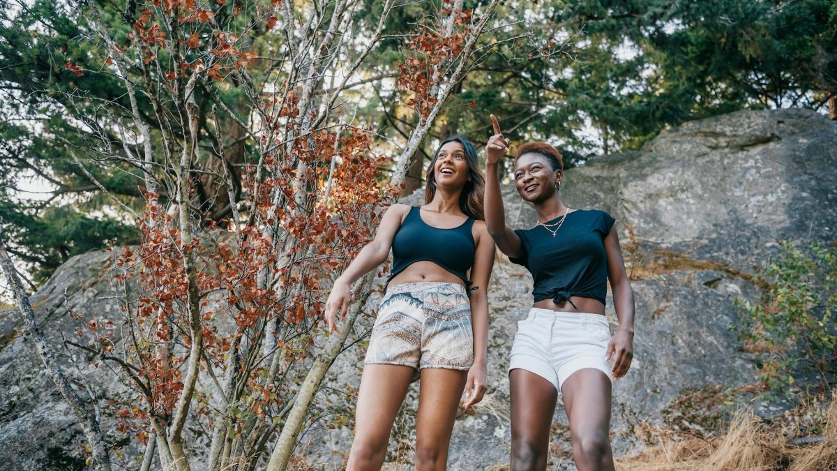 Two diverse women hiking and enjoying nature in an autumn forest scene.
