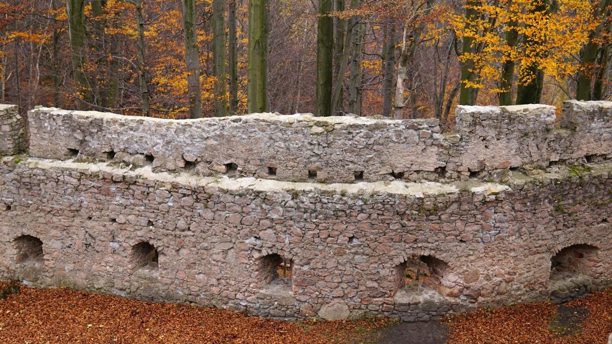 Explore ancient stone ruins surrounded by autumn trees and fallen leaves.