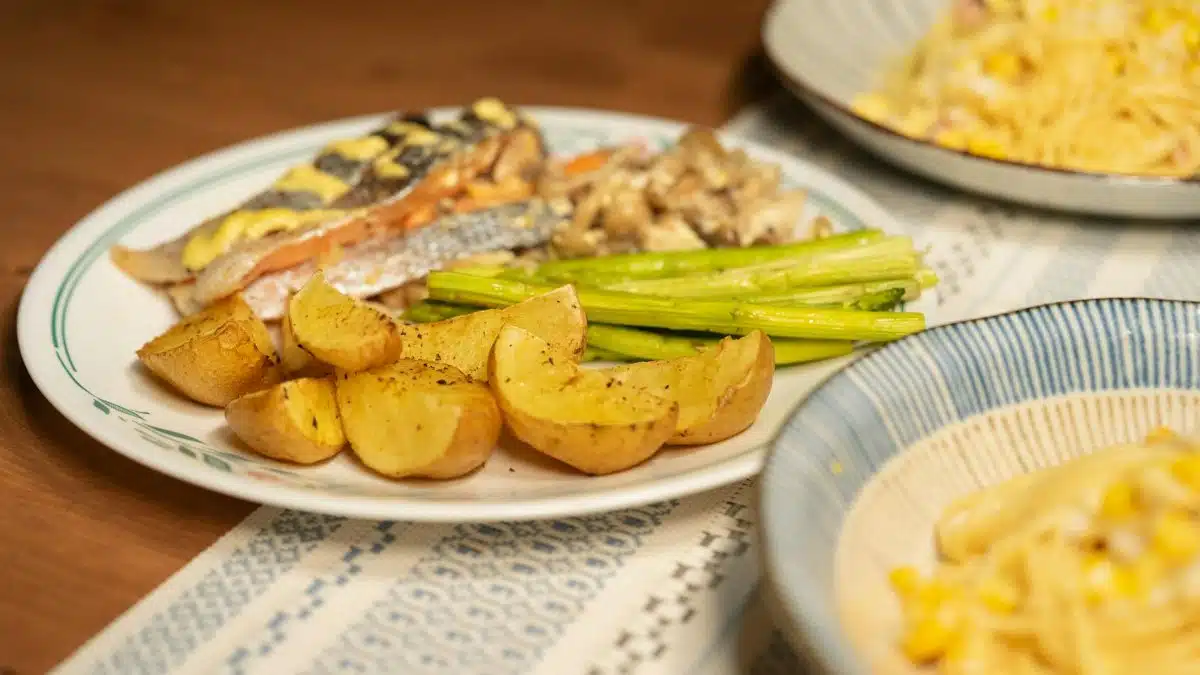 A visually appetizing serving of grilled salmon, roasted potatoes, and asparagus plated with pasta for a gourmet experience.