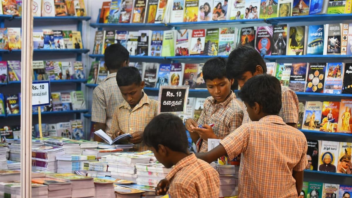 Children engaged in browsing books at a stall in Madurai, highlighting interest in reading and education.