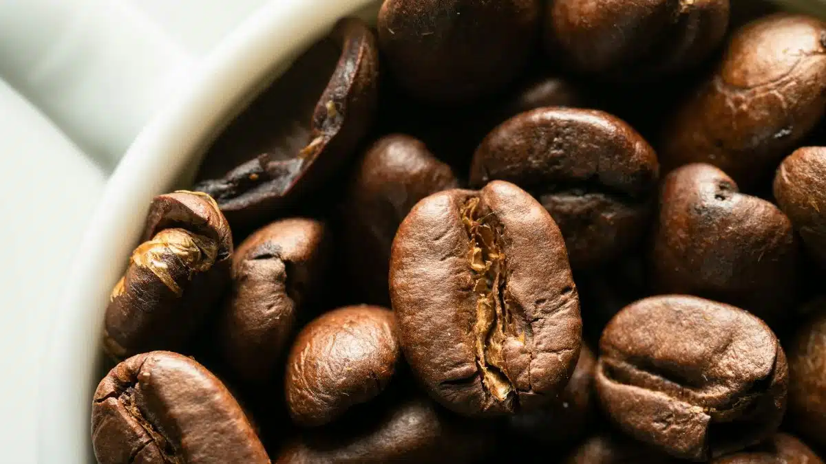 Macro shot highlighting the texture of roasted coffee beans inside a mug.