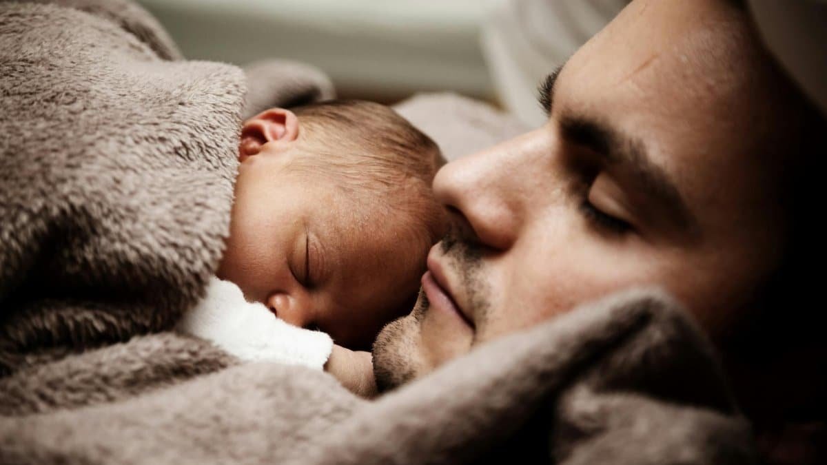 A touching close-up of a father and his baby peacefully napping together.