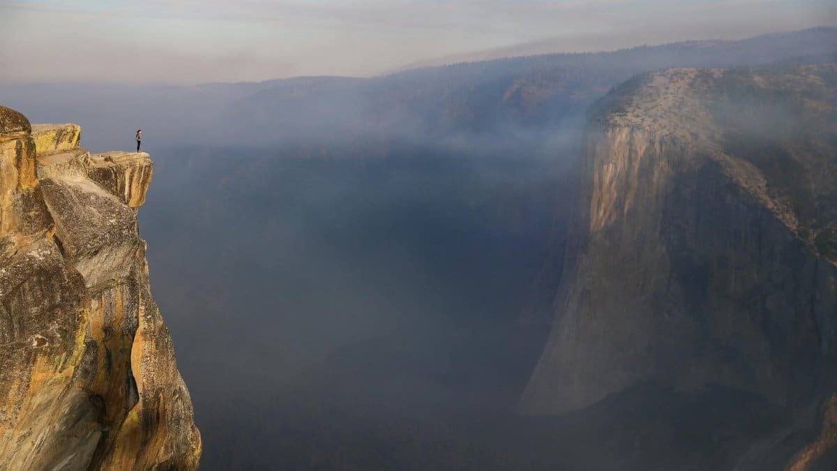 Breathtaking view of a lone hiker atop Taft Point in Yosemite National Park.